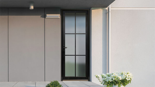 A sleek and modern single door featuring a matte black frame with narrow-profile simulated divided lite (SDL) glass panels. The door is set against a minimalist exterior with contrasting gray and white stucco walls. A clean concrete porch and potted plants enhance the contemporary look.